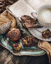 A cozy autumn setting featuring pumpkin muffins, a warm cup of coffee, and an open book. The scene