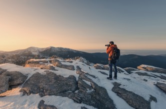 A photographer in an orange jacket captures the snowy landscape of Siete Picos, part of the