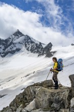 Mountaineer on a rock between snow, descent from the summit of Schönbichler Horn, view of
