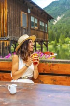 Woman relaxing at lake dobbiaco with a mug, enjoying the mountain landscape in the dolomites