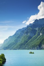 Sunny view over Lake Walen with the small chive island in the turquoise water and mountain range