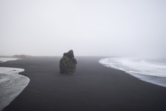 A haunting view of Reynisfjara Beach, Iceland, featuring a solitary rock formation amidst the black