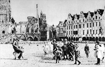 Première Guerre Mondiale. Après le bombardement, un soldat amuse les enfants sur la grande place d'Arras