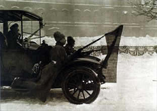 Russian Revolution of 1917. In Petrograd, soldiers riding on the running board of an automobile with red flags attached to their bayonets