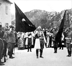 With the keys of Scutari in one hand, King Nicholas of Montenegro, unfolds a flag captured from the Turks in front of his subjects (1913)