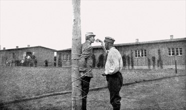 Première Guerre Mondiale. Au camp de Zwickau, un prisonnier français, lié au poteau, reçoit un verre d'eau d'un prisonnier roumain