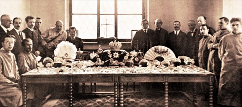 Russian Imperial crown jewels displayed on a table around which is seated the commission in charge of their security (1922)