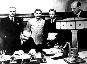 Signing of the Germano-Soviet Non-Agression Pact in Moscow. Molotov signs. Behind him, Ribbentrop and Stalin