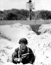 Débarquement en Normandie. Soldat américain camouflé dans une tranchée, surveillant la plage