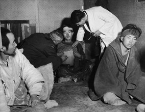 Réfugiés de l'île de Koje. Le docteur Henri Meyer ausculte un réfugié que le docteur coréen soupçonne d'avoir contracté le typhus. 1951.