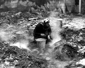 Femme belge récupérant des céréales d'une grange détruite, 1944