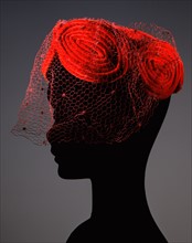 Red velvet toque with tubular decoration of the same colour with