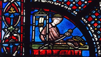 Un épicier avec des pains et fruits devant lui (vitrail de Chartres)