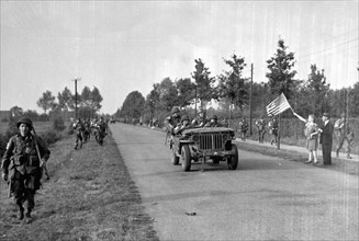 Des hollandais agitent un drapeau américain devant les troupes de parachutistes américains, près de Zon en Hollande. (18 septembre 1944)