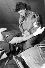 Une infirmière de l'armée US prend la tension d'un blessé dans un hôpital d'évacuation en Normandie. (été 1944)