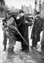 Un soldat américain fouille des civils allemands à Krefeld en Allemagne. (mars 1945)