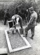 Un ancien membre du parti Nazi nettoie une tombe du cimetière juif de Bergheim (28 juillet 1945)