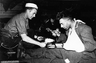 Un marin américain aide un prisonnier allemand (juin 1944, après le Jour J)