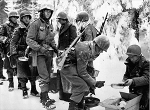 En marche vers Laroche (Belgique), des soldats américains s'arrêtent pour se nourrir (13 janvier 1945).