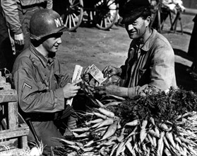 Un soldat américain fait son marché à Cherbourg (France). juin 1944