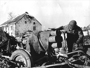Soldat américain examinant un canon à obus allemand hors d'état à Tarchamps (Luxembourg) 1945