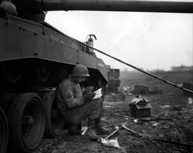Caporal de l'armée U.S lisant le manuel d'instructions du char General Pershing (Allemagne). 29 mars 1945