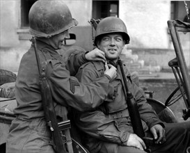 Un caporal américain aide un sous-lieutenant fraîchement nommé à mettre ses galons. (Rambervillers en France, le 2 décembre 1944)