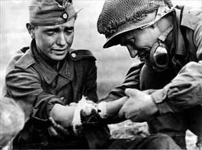 A U.S soldier looks at the wounded arm of a German soldier in France (Autumn 1944)