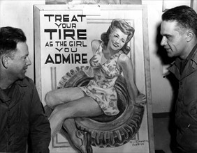 Soldats américains admirant une affiche publicitaire de pneus dessinée par un de leur camarade. (France, 7 janvier 1945)