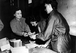 En Grande-Bretagne, un officier du corps d'armée féminin U.S. distribue des devises françaises.
(1944)