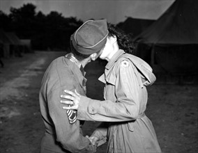 Sergent de l'U.S. Army embrassant une jeune femme du corps d'armée féminin U.S.
(25 Juillet 1945)