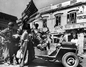 A Messine, en Sicile, les civils offrent des fleurs aux soldats américains.
(24 août 1943)