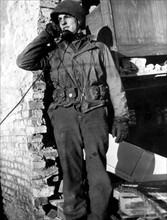 Un soldat américain téléphone d'un bâtiment allemand bombardé, à Aldenhoven.
(26 décembre 1944)
