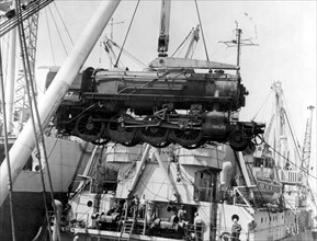 A heavy American freight engine is swung ashore at Cherbourg harbour in France, Autumn 1944