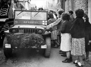 Civils français se pressant autour d'une jeep de la 2e D.B. en Normandie.
(Eté 1944)