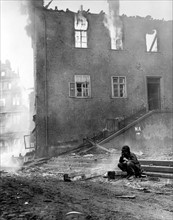 Soldat américain vérifiant les lignes téléphoniques dans Gemunden en feu, en Allemagne.
(6 avril 1945)