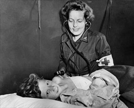 Infirmière de l'U.S. Army soignant un enfant français blessé en Normandie.
 (Eté 1944)