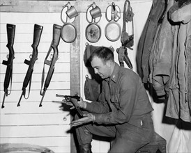 Un lieutenant de l'U.S. Air Force examine un revolver Luger, confisqué aux Allemands.
(France, janvier 1945)