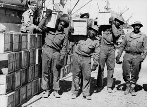Des soldats noirs déchargent du matériel sur un dock du Moyen-Orient.
 (Avril 1943)