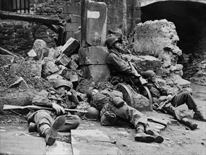 Des soldats américains se reposent dans les rues dévastées de Fulda, en Allemagne. 
(3 avril 1945)