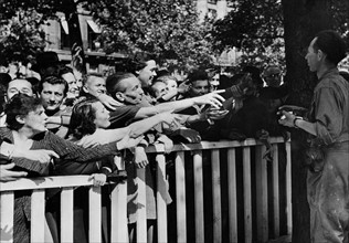 A Paris, les soldats français distribuent bonbons et cigarettes (25 août 1944)