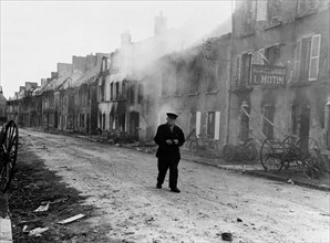 Un vieil homme marche dans les rues de Montebourg, en Normandie.
 (Juin 1944)
