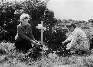 Deux Françaises fleurissent la tombe d'un parachutiste américain en Normandie.
 (Juin 1944)