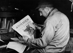 Un soldat américain lit un journal nazi, à Carentan, en Normandie.
 (Juin 1944)