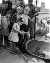 Près de Reims, une fillette baptise un "bateau" avec une bouteille de Coca-Cola. 
(7 août 1945)