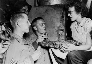 A member of the American Red Cross clubmobile gives doughnuts to GI's in Normandy, Summer 1944