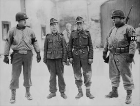 American soldiers guard Nazi prisoners near Bastogne, January 1945