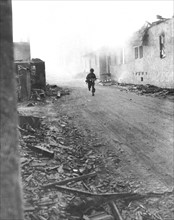 American soldier advances in burning Rechtenbach, March 24, 1945