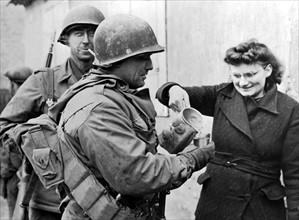 Jeune alsacienne versant un verre de vin  aux soldats U.S. à Drusenheim
(Hiver 1944-45)