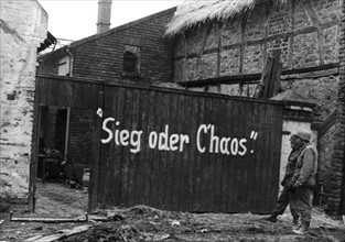 Soldats du génie américain lisant un un slogan écrit sur une palissade à Vettweiss
(Mars 1945)